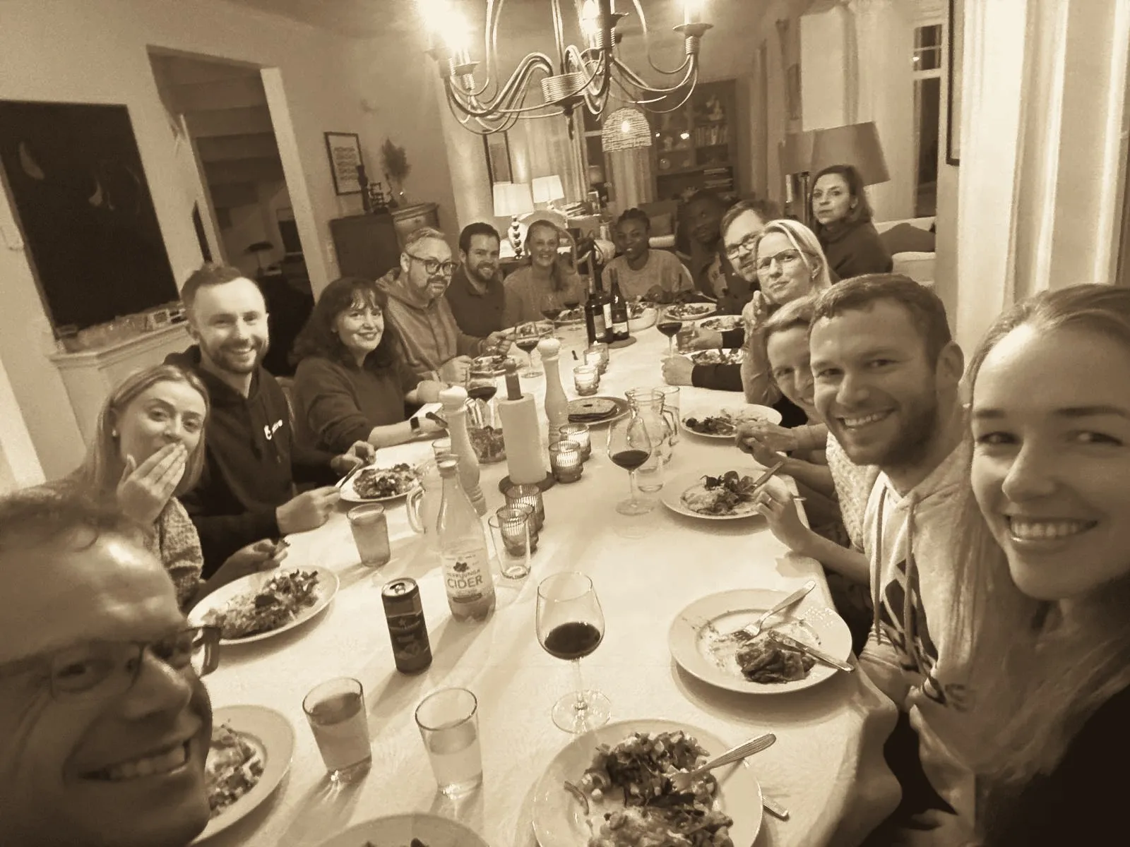 Church members sharing a meal around a long dinner table in a home