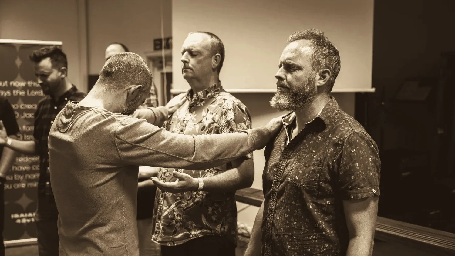 People laying hands on a man and praying for him at a Relational Mission prayer gathering